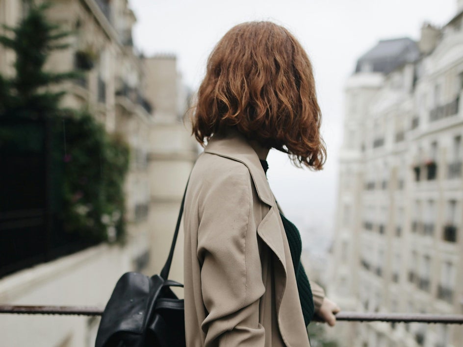 woman in trench coat on bridge